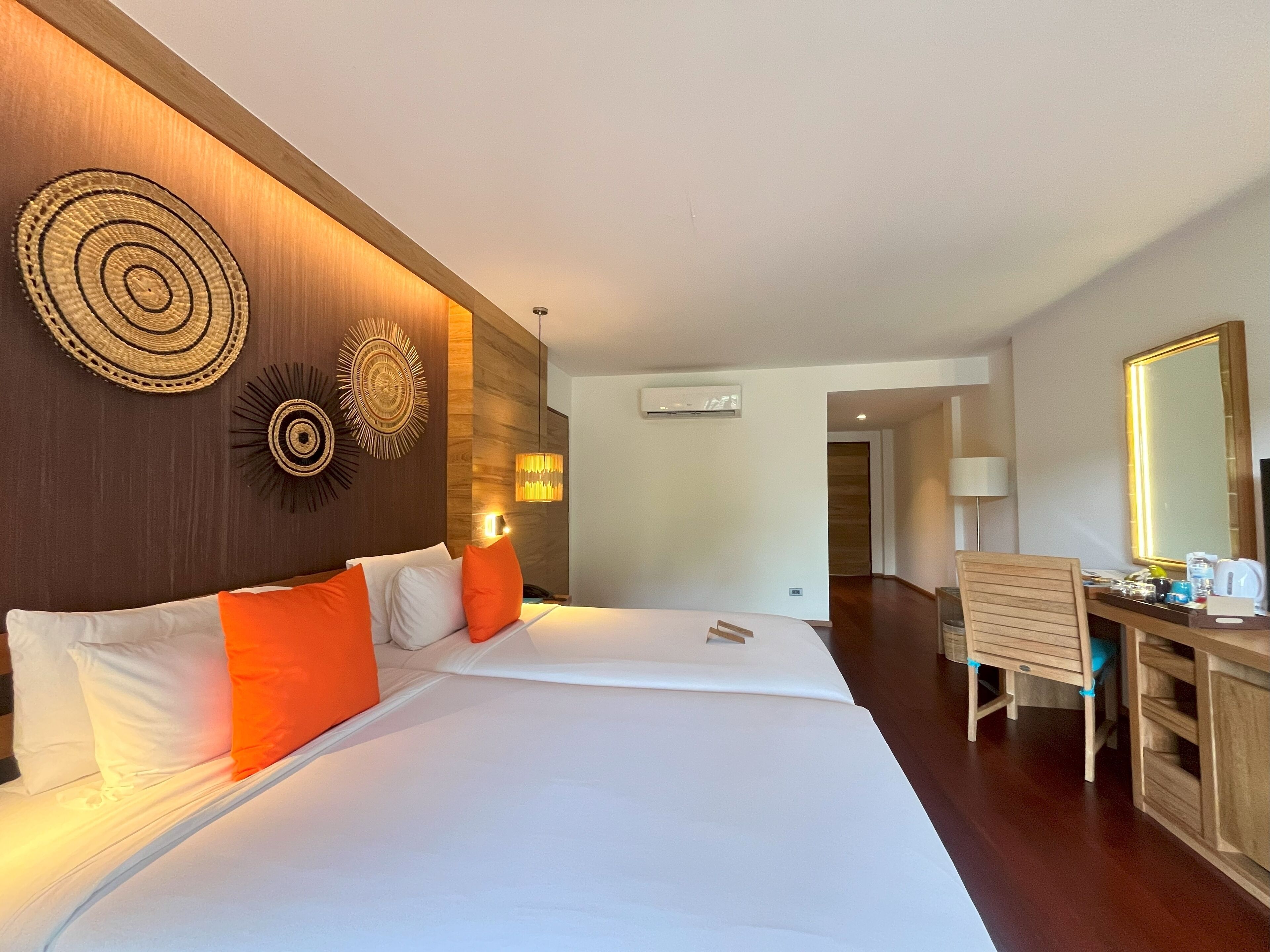 Camera d'albergo con un letto grande, una scrivania in legno e uno specchio.