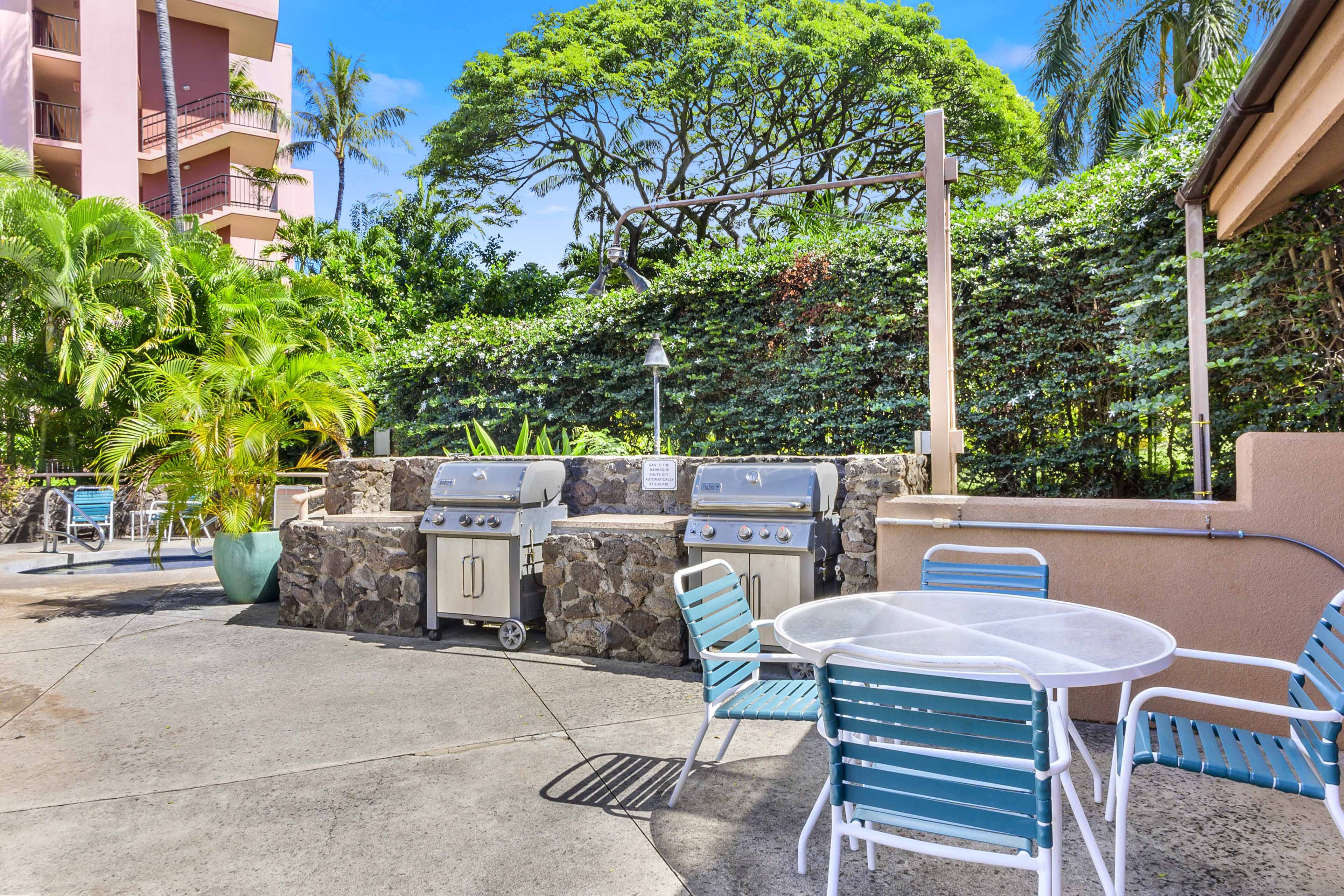 An outdoor patio with a grill, chairs, and a table.