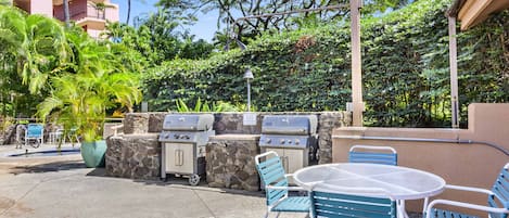 An outdoor patio with a grill, chairs, and a table.
