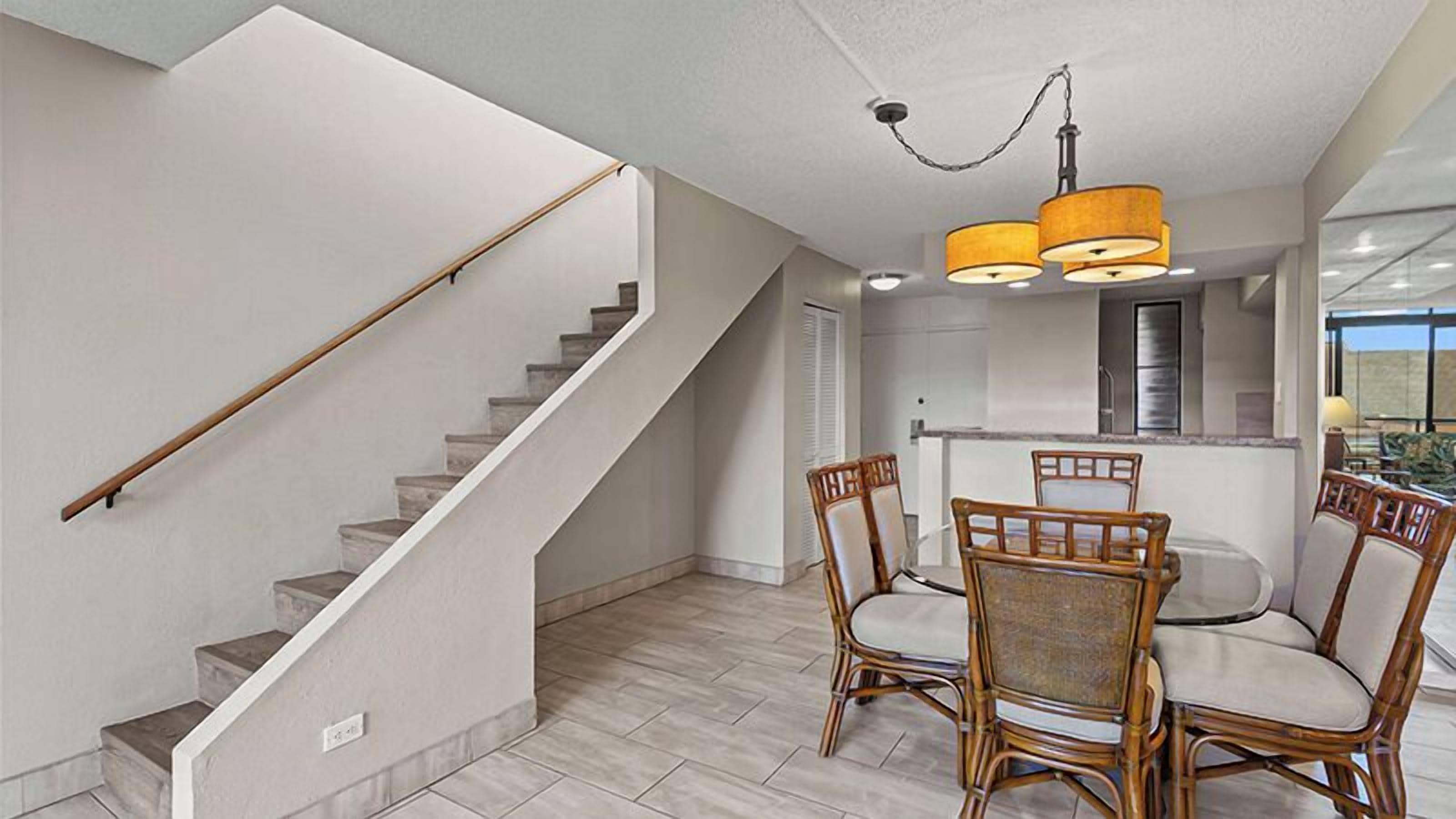 A modern interior with a staircase, dining area, and kitchen.