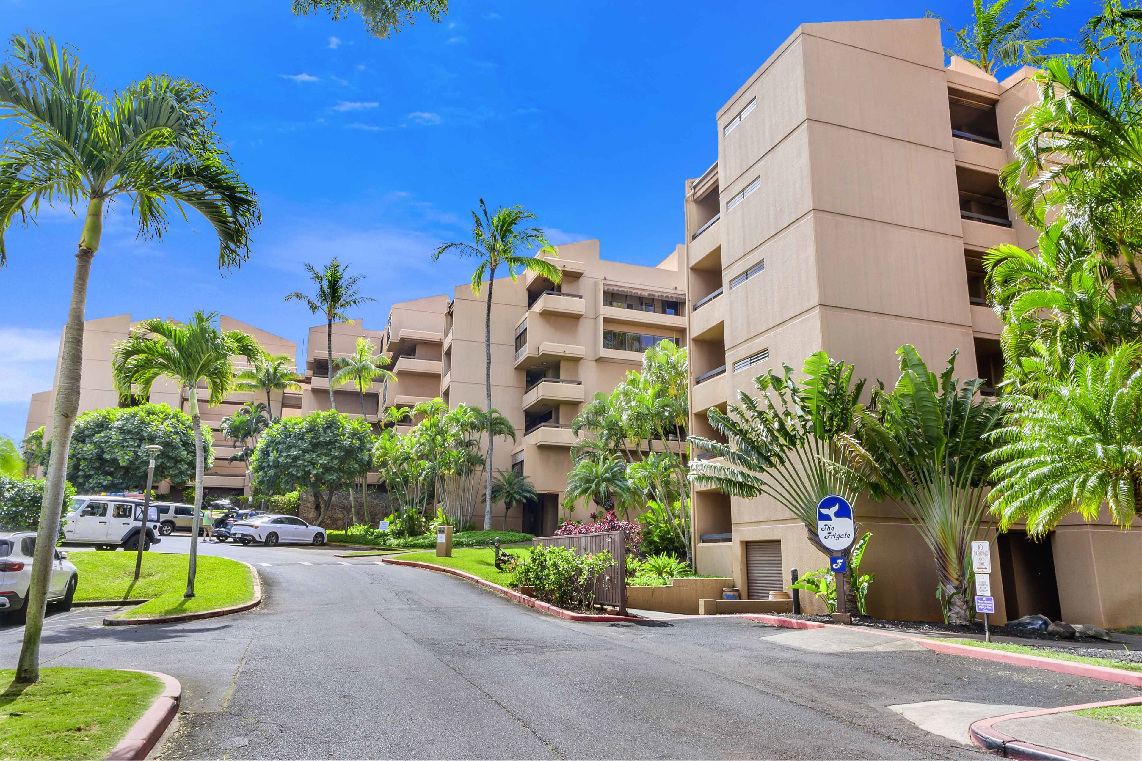 A multi-story hotel with a central courtyard, palm trees, and a clear blue sky.