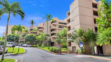 A multi-story hotel with a central courtyard, palm trees, and a clear blue sky.