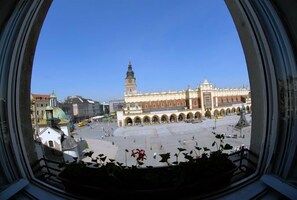 A view of a spacious square with a prominent building featuring a clock tower and arched colonnades. - Hostel Rynek 7 - Hostel (Kraków)