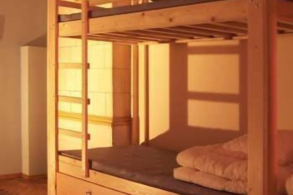 A bunk bed with a wooden frame, a small clock, and a storage drawer.