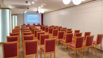 A conference room with rows of wooden chairs and a projection screen.