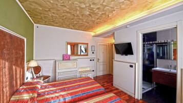 Une chambre à coucher comprenant un lit, une commode, un miroir et un téléviseur fixé au mur.