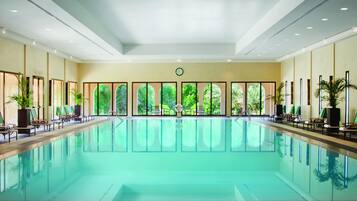 Una piscina techada, una piscina al aire libre, sombrillas