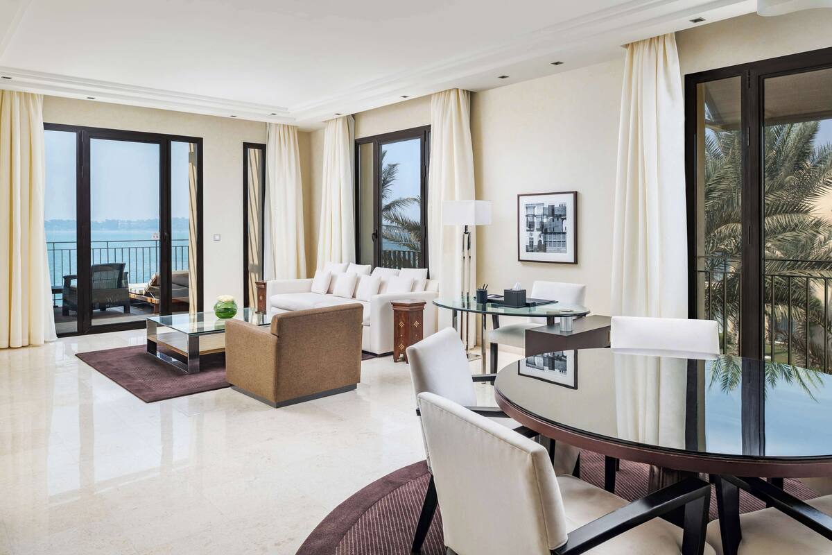 Une chambre d’hôtel moderne avec une table en verre, un canapé blanc et une vue sur la mer.