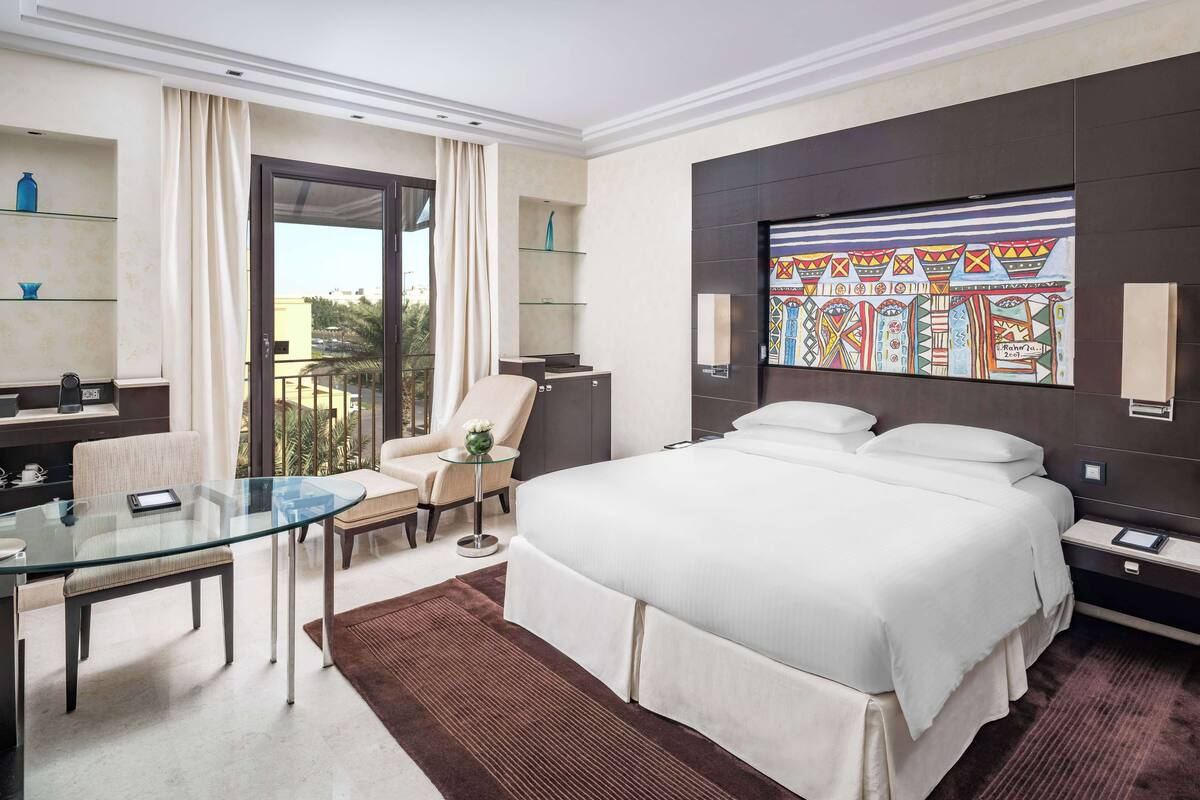 Une chambre d’hôtel moderne dotée d’un grand lit, d’une table en verre, d’un canapé, d’un bureau et d’un balcon avec des rideaux.