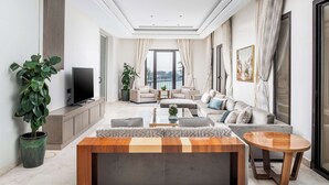 Una sala moderna con un televisor de pantalla plana grande, una mesa de centro de madera y un conjunto de sofás.