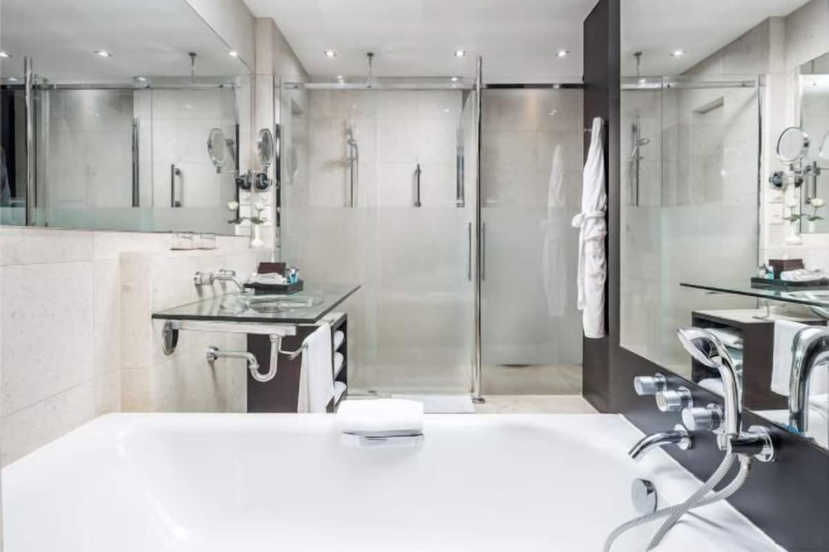 Een aparte badkuip en douche, een regendouche, designer toiletartikelen