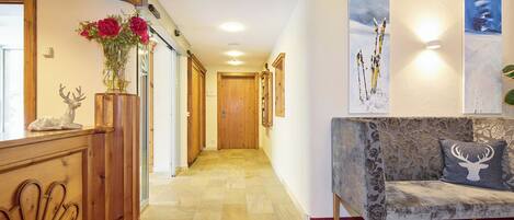 A hallway with wooden flooring, a red carpet, a wooden reception desk, and a sofa with a floral pattern.