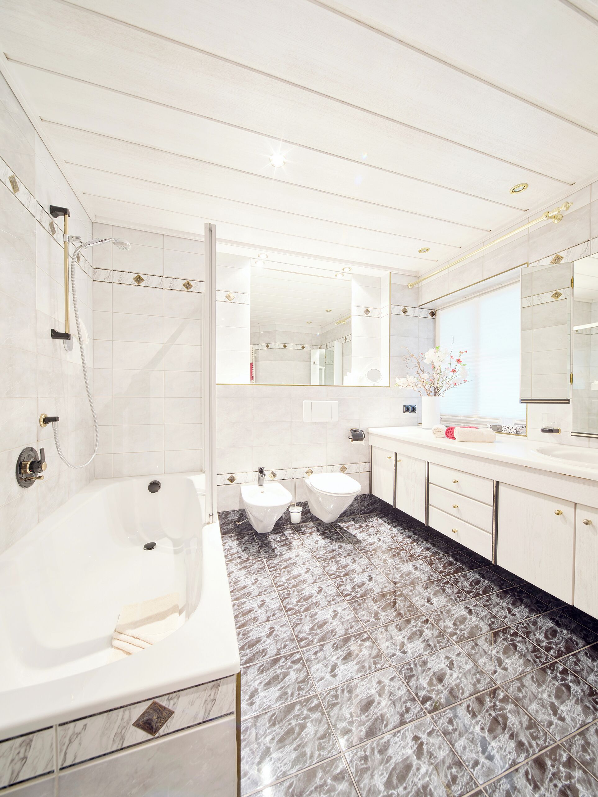 Ein modernes Badezimmer mit Badewanne, zwei Waschbecken und einer Dusche.