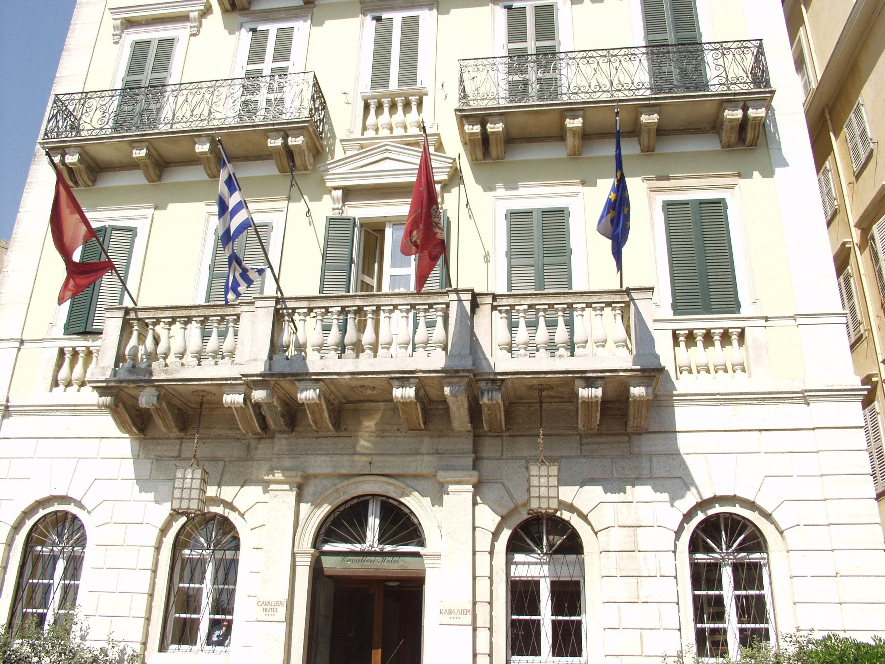 A historic building with a classical facade, multiple balconies, and flags.