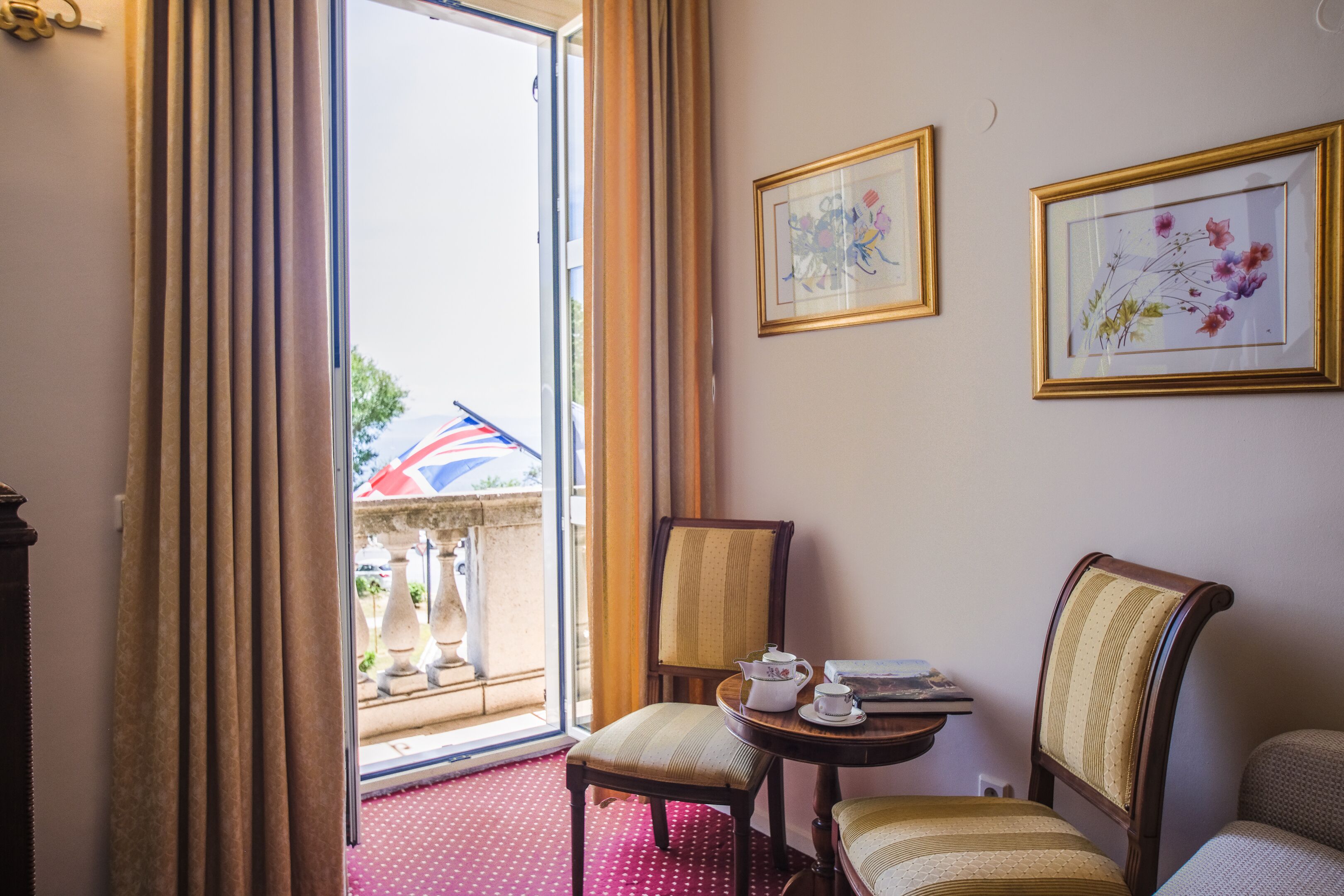 Habitación de hotel con vistas al exterior, una mesa de comedor con una silla y dos cuadros en la pared.