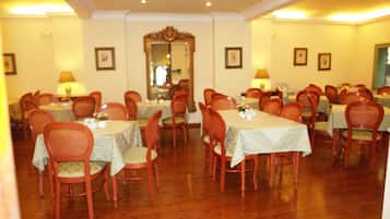 A dining area with multiple tables and chairs, a mirror, and framed pictures on the walls.