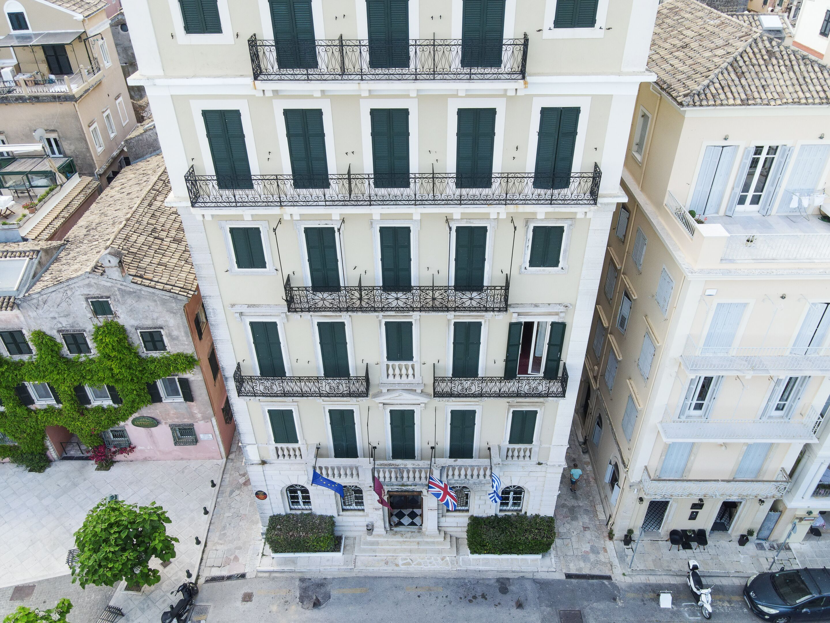 A multi-story building with balconies, a flag, and a paved street.