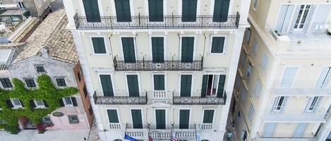 Un edificio de varios pisos con balcones, una bandera y una calle pavimentada.