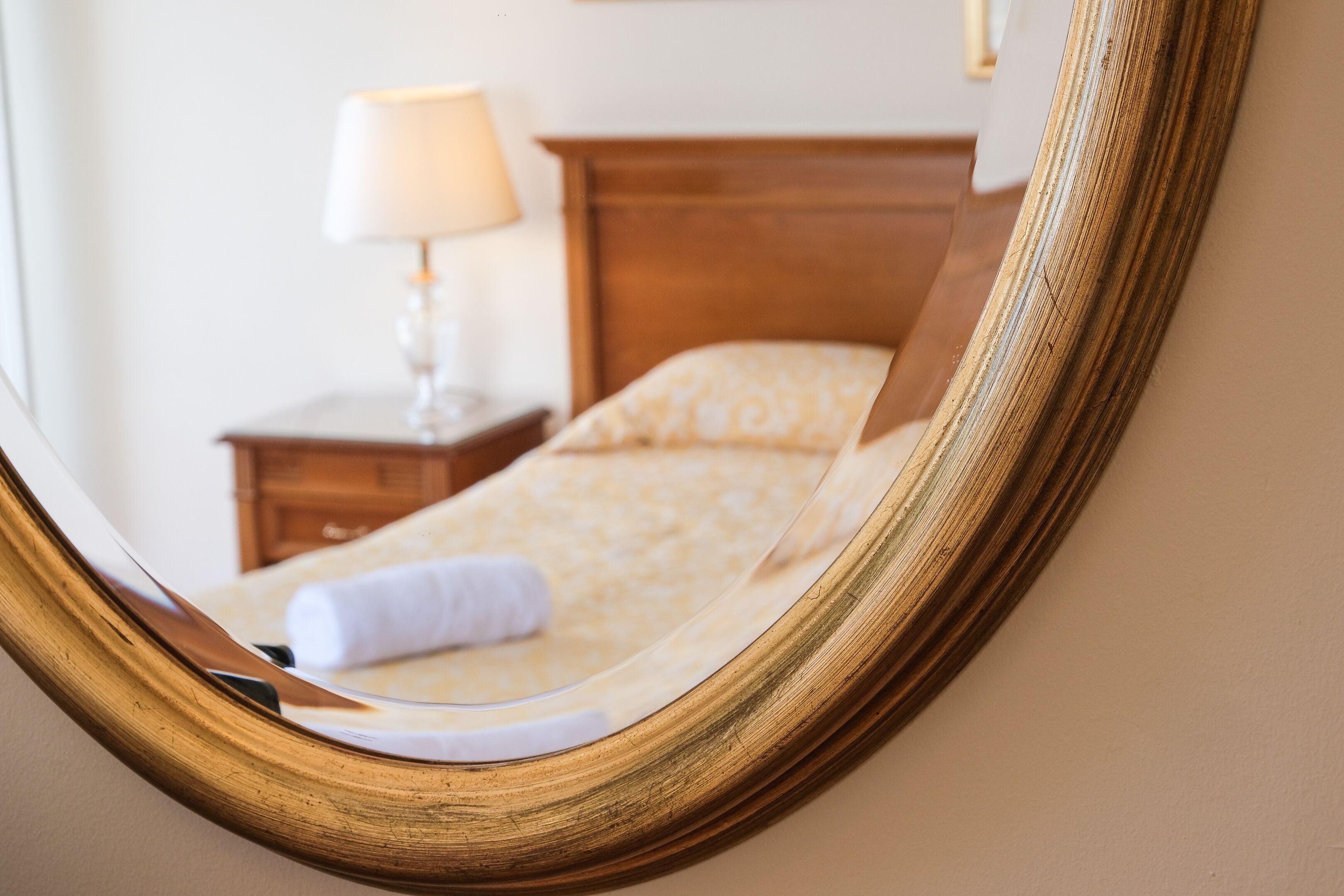 A bedroom with a wooden headboard, a bedside table with a lamp, and a patterned bedspread.