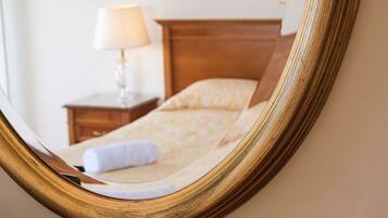 Un dormitorio con cabecera de madera, mesita de noche con lámpara y colcha estampada.