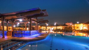 Ein Pool mit einer Sitzecke im Wasser und einer überdachten Terrasse.