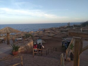 A beachside area with outdoor seating, umbrellas, and a view of the sea. - Tivoli Hotel Aqua Park (Sharm El Sheikh)