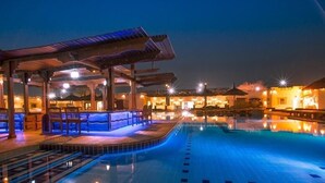 Ein Poolbereich bei Nacht mit überdachter Sitzgelegenheit und Pool.
