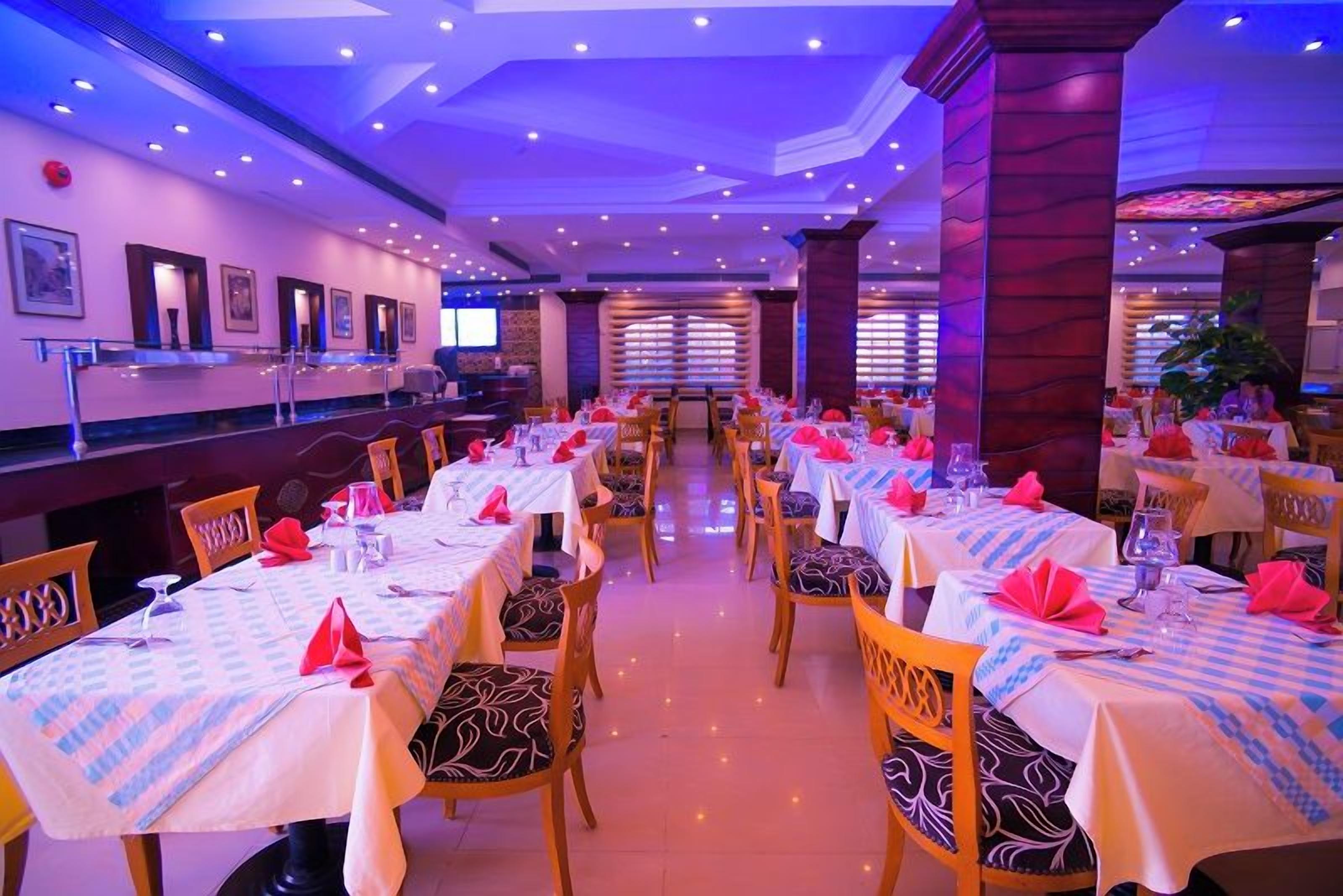 Un restaurant où de nombreuses tables sont dressées pour le service, chacune étant recouverte d’une nappe et agrémentée d’une serviette.