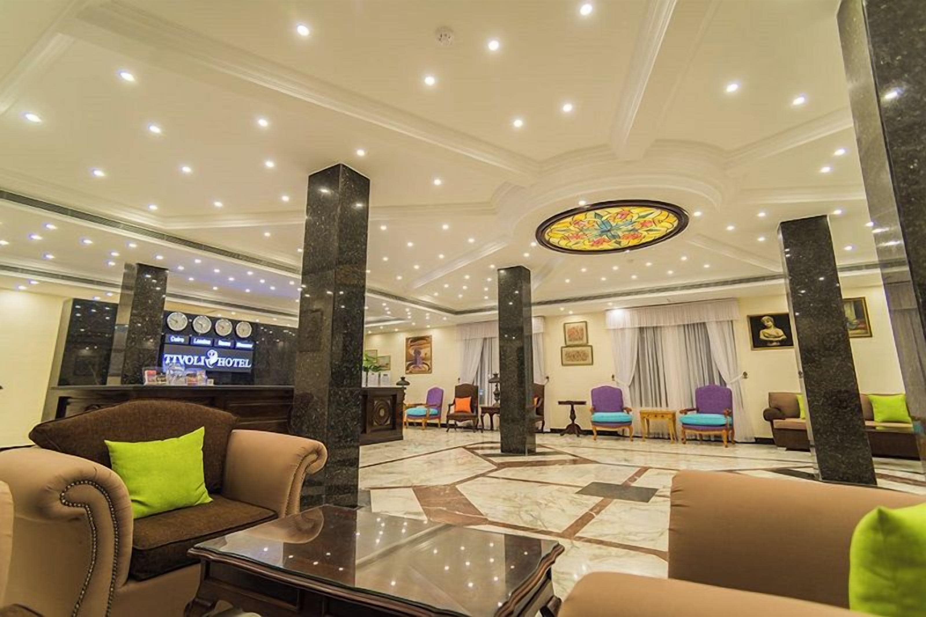 Eine Hotelhalle mit einer Rezeption, einer Sitzecke und einem großen Buntglasfenster.