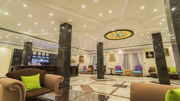 Eine Hotelhalle mit einer Rezeption, einer Sitzecke und einem großen Buntglasfenster.