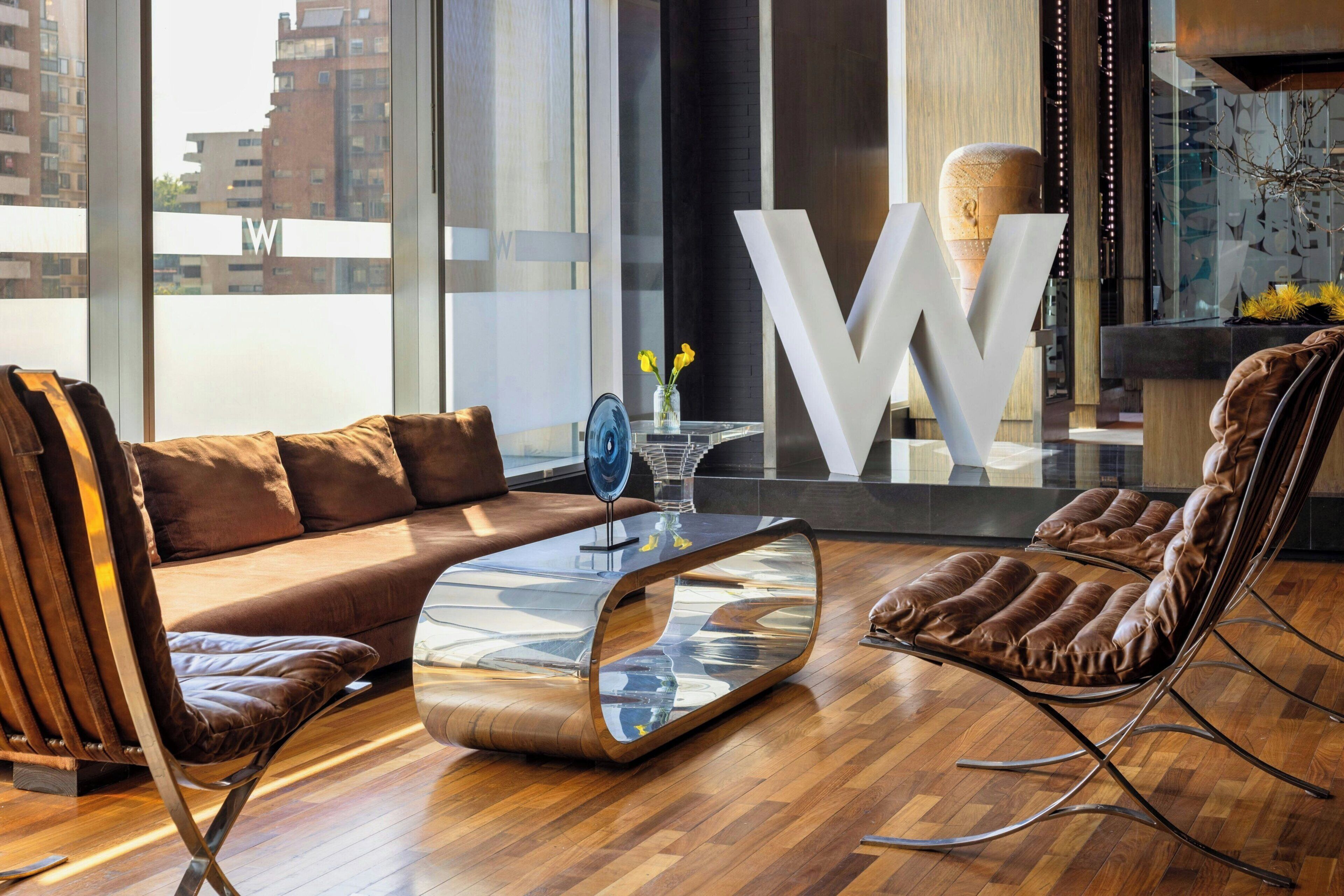 A modern living room with a brown leather sofa, a glass coffee table, and a brown leather chair.