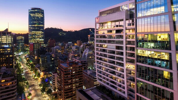 Un paisaje urbano con modernos rascacielos, incluyendo un edificio destacado con el logotipo 'VW'.