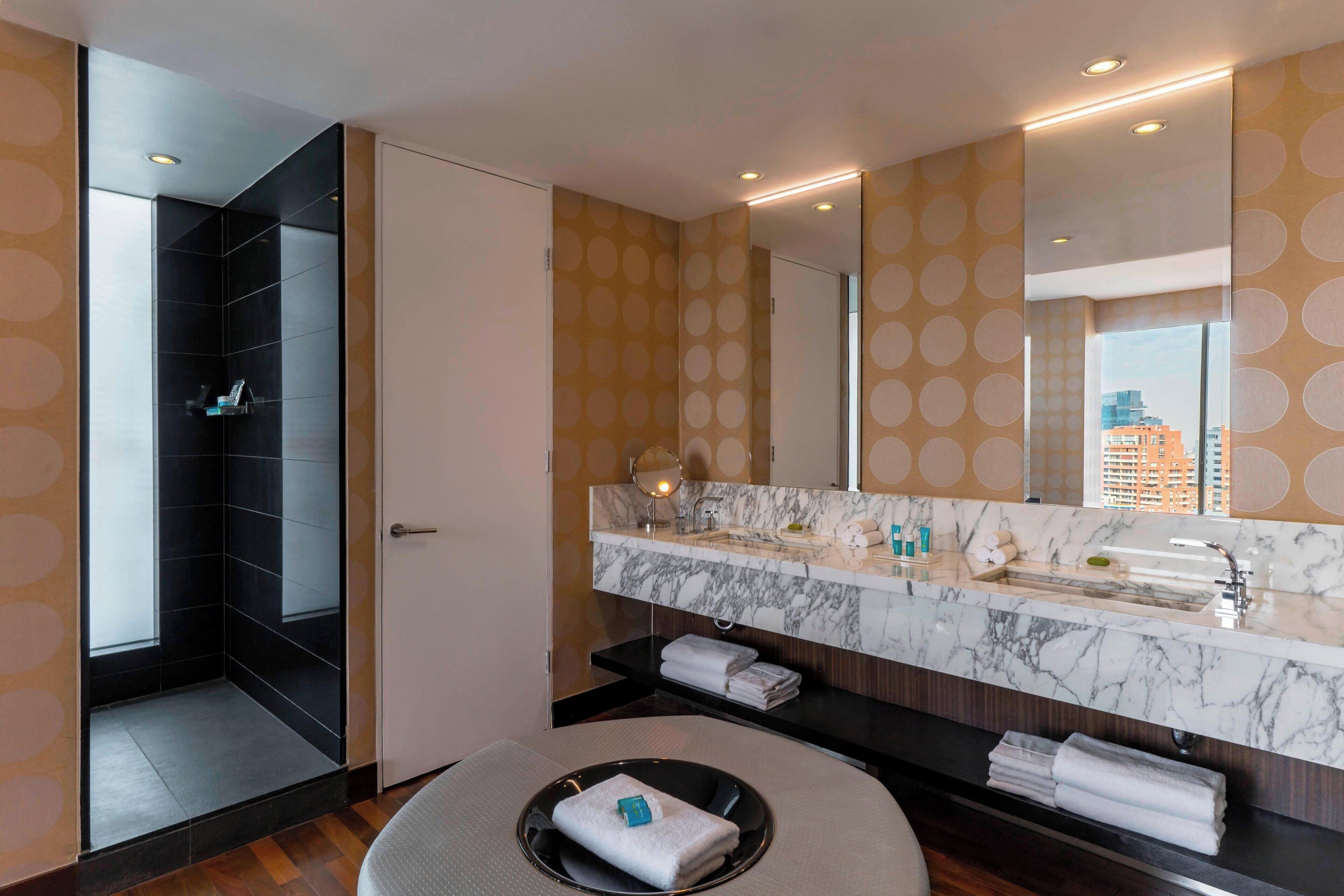 Een moderne badkamer met een grote spiegel, een marmeren aanrecht en een douche.