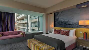 Ein Hotelzimmer mit Bett, Sofa, Sitzbank, einem großen Fenster und Blick auf ein Gebäude.