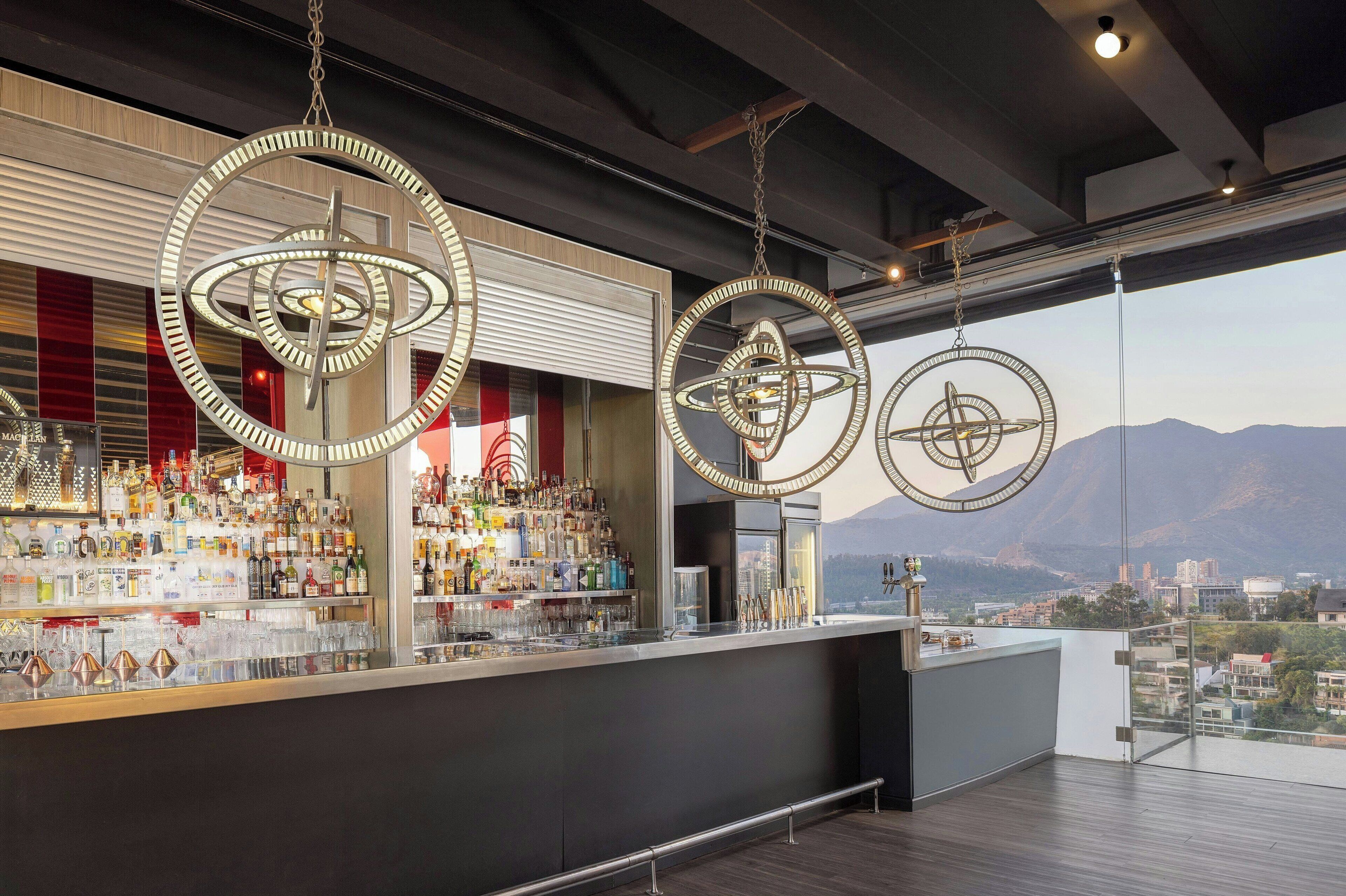 Een bar met meerdere hanglampen en uitzicht over de stad.
