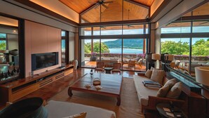 Un salón amplio con un televisor grande, asientos cómodos y vistas al exterior.