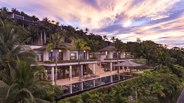 Un resort lujoso con una amplia piscina infinita, numerosas habitaciones y exuberantes alrededores tropicales.