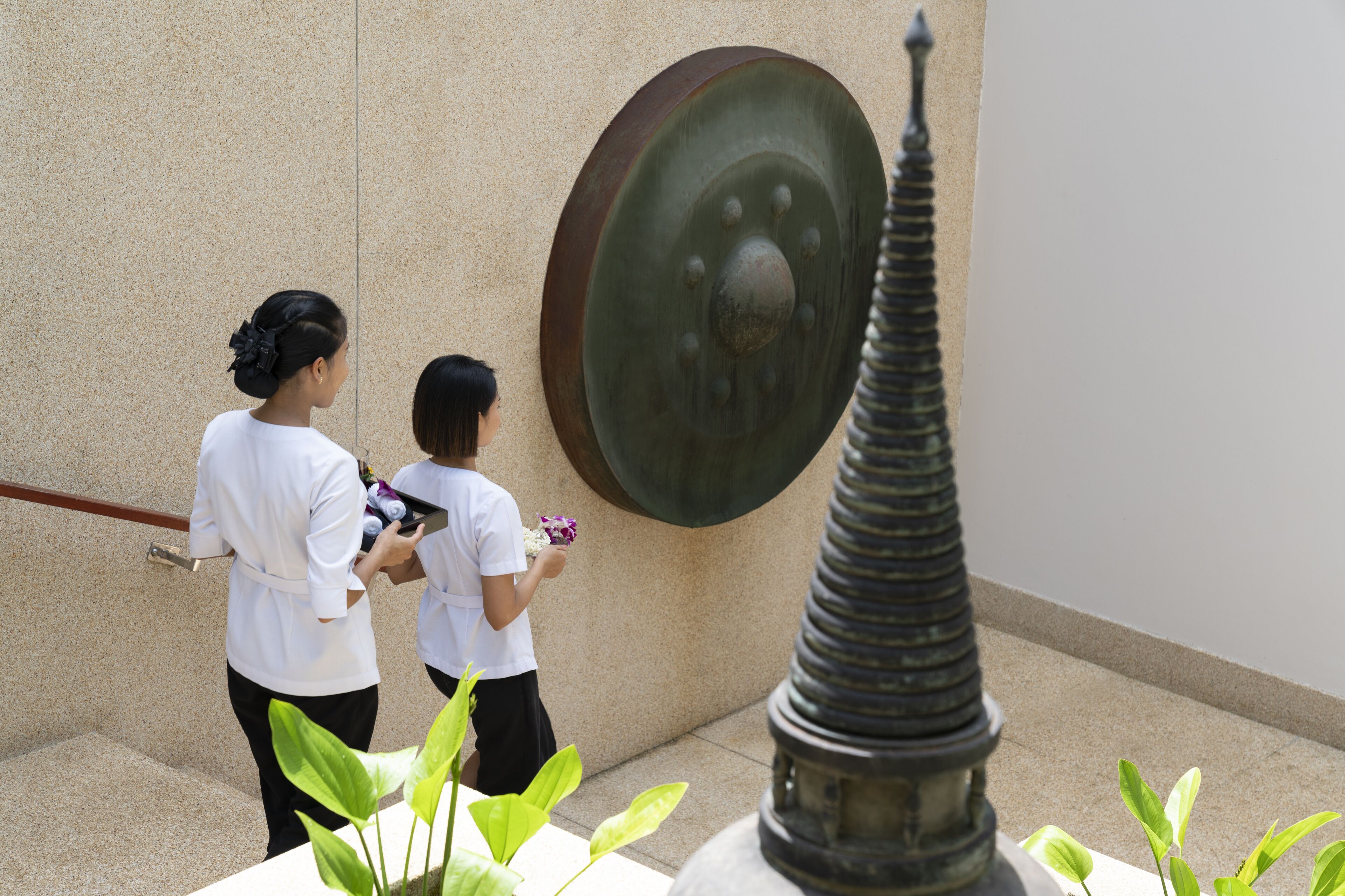 A person holding a flower near a large metal sculpture.