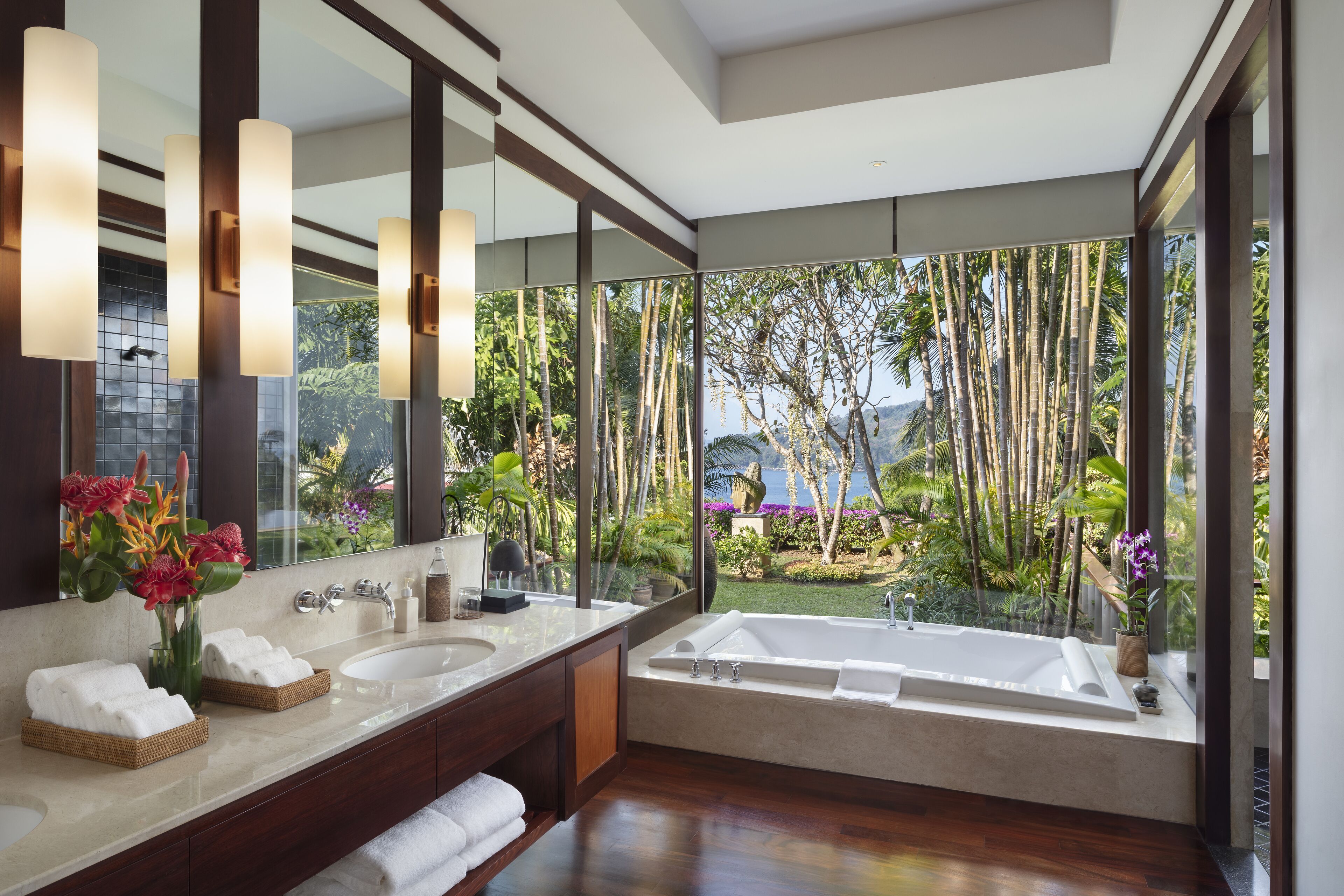 A modern bathroom with a large bathtub, two sinks, and a large mirror.