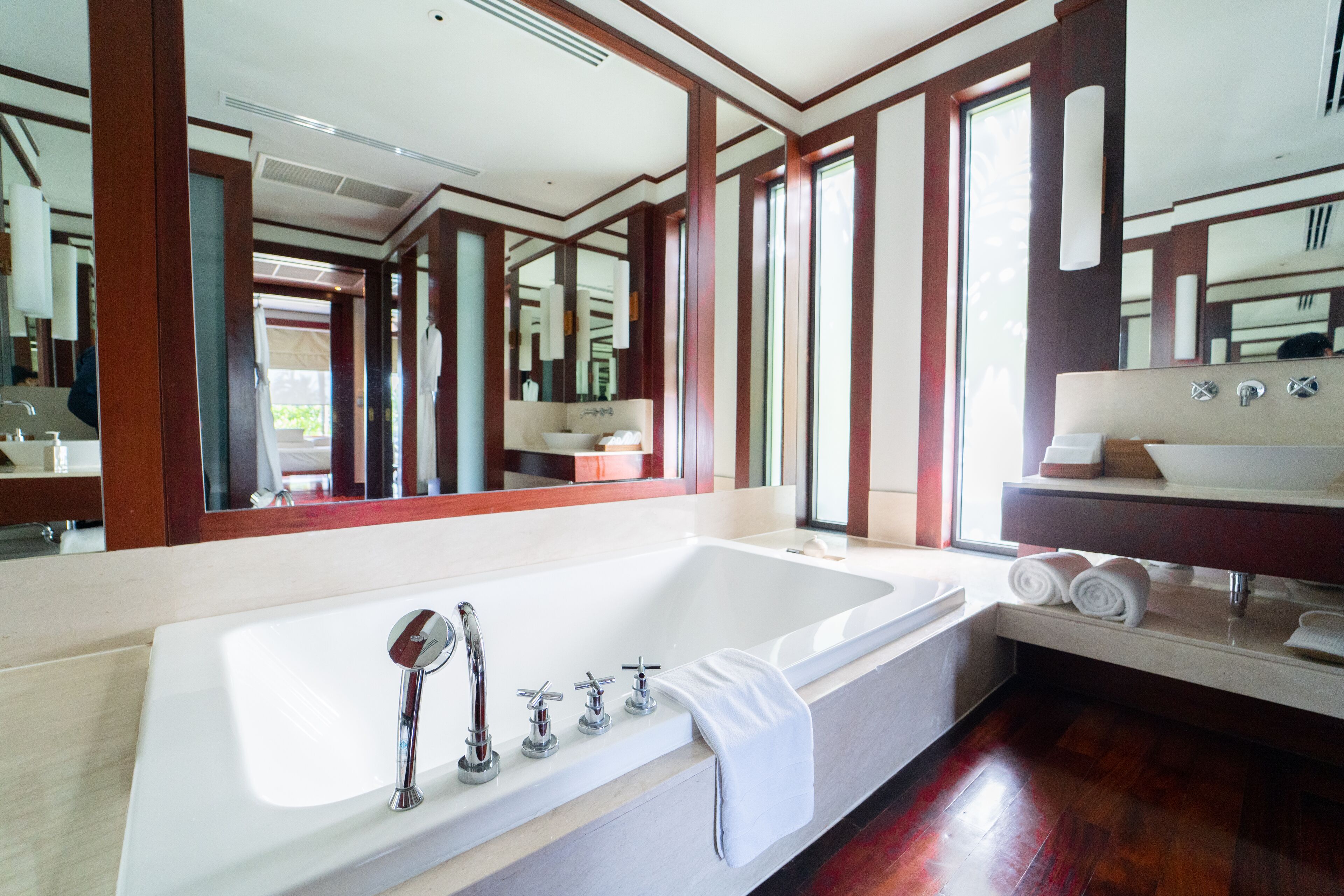 A modern bathroom with a large bathtub, a vanity with a sink, and a mirror.
