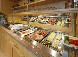 Buffet com diversas opções de comida, incluindo carnes, queijos e saladas.