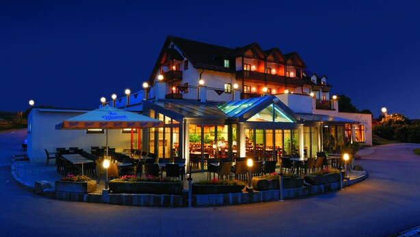 A two-story building with a restaurant on the ground floor, outdoor seating, and a covered patio area.