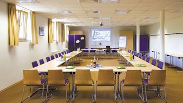 A conference room with a long table, chairs, a projector screen, and a whiteboard.