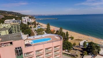 Hotel com piscina no terraço, vista para a praia e várias varandas com espreguiçadeiras.