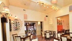 A restaurant with multiple tables and chairs, a wine rack on the wall, and a warm lighting ambiance. - The Fontana Hotel (Novi Sad)