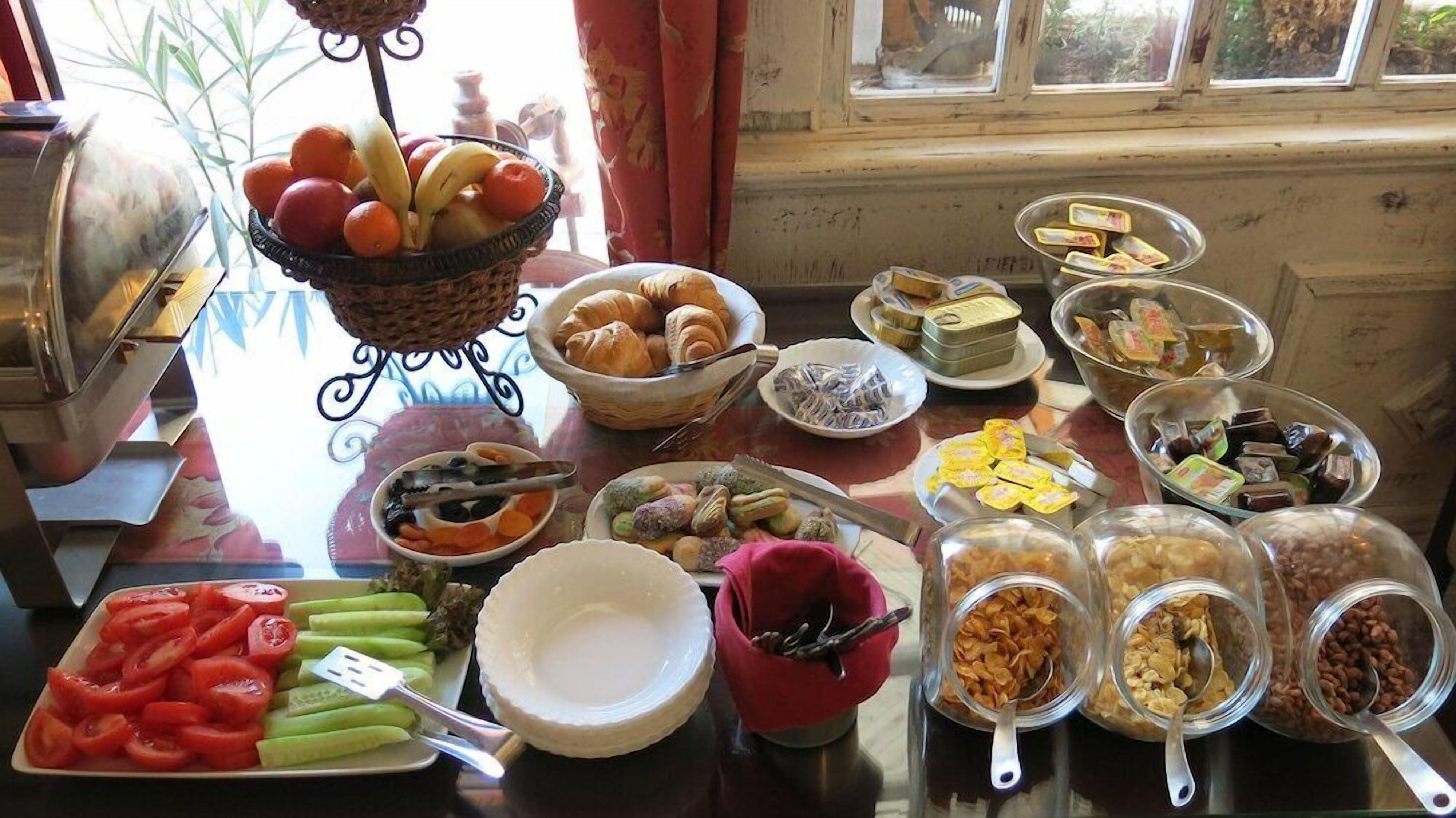A buffet table with various food items including fruits, pastries, and condiments.