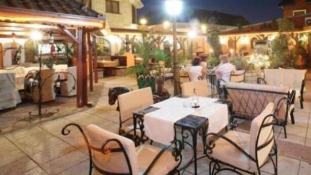 An outdoor dining area with tables and chairs, surrounded by buildings and plants. - The Fontana Hotel (Novi Sad)