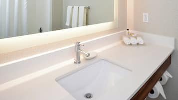 A modern bathroom with a white sink, a large mirror, and a towel rack with towels.