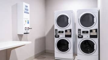 Une buanderie équipée de deux machines à laver à chargement frontal, d’un évier et d’un distributeur de savon fixé au mur.