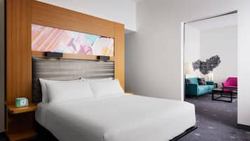 Ein Hotelzimmer mit einem großen Bett, einem Holz-Kopfteil, einem Nachttisch mit einer Uhr und einem Wandbild.